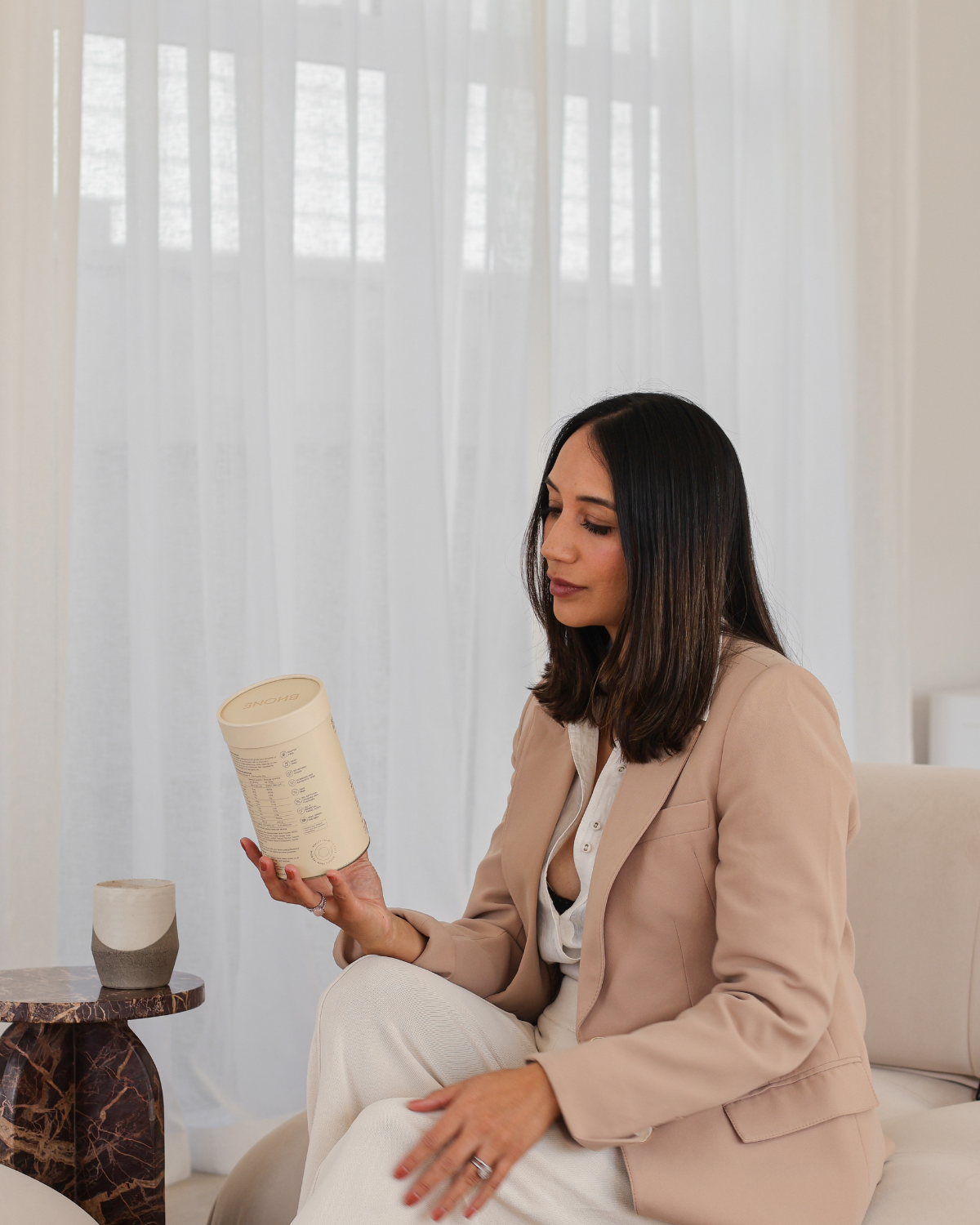 Renei, founder of Bhone, holding a cup of bone broth hot drink and the product in her hand