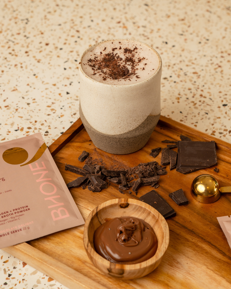 Chocolate-themed setup with a cup, chocolate powder, and Bhone supplements on a wooden board.